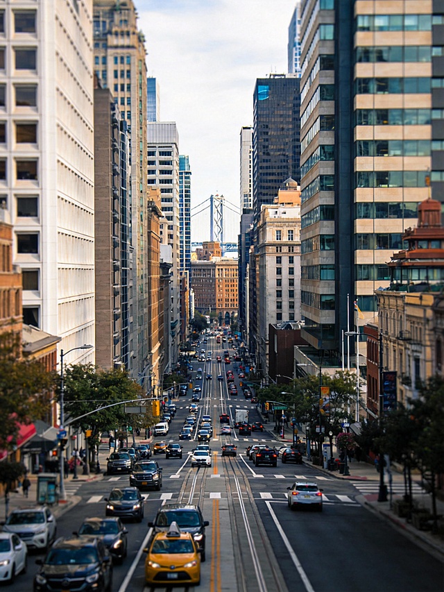 画面：美国城市白天街景，高楼林立，车流正常
运镜方案：稳定广角推进，交代宏观背景