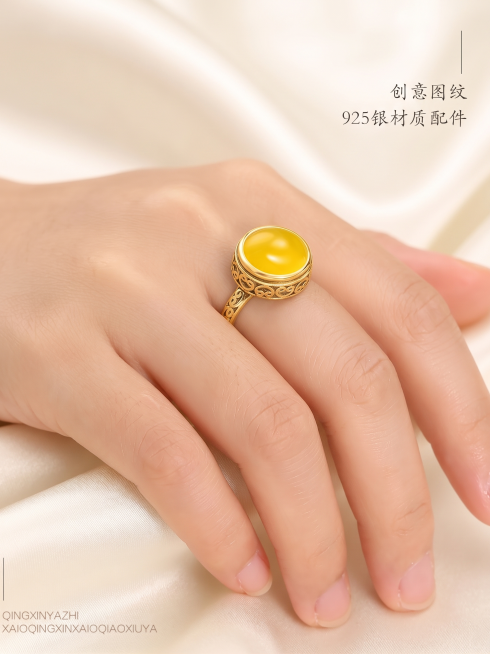 将戒指金属部分颜色改为亮金色，保留黄色宝石和产品细节，保留手上佩戴场景和所有文字内容，将背景替换为高级质感的米白色丝绸预览效果