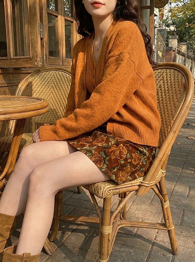 保留这套秋日焦糖色系穿搭，变换模特坐姿，聚焦展示碎花半裙的花色和针织开衫的软糯质感，复古咖啡馆露台暖金色午后阳光，慵懒氛围，抖音带货风格，凸显服饰细节