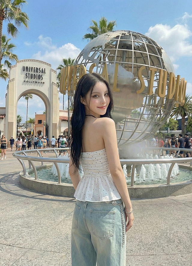 保持模特和服饰不变，背景为环球影城，生成背面回头看向镜头的姿势图片