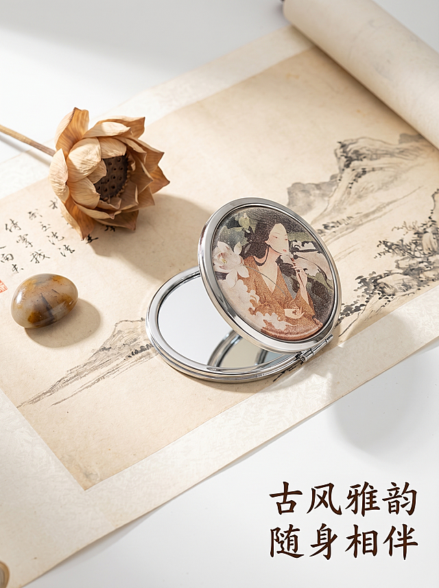 [主图 5] 国风意境展示整体产品；
[氛围风格] 国风艺术意境，雅致古典；
[画质] 商业摄影质感、光线柔和通透、产品清晰真实、画面高级有氛围。
[元素] 打开的双面折叠随身镜放置在中式卷轴宣纸之上，旁边摆放一枝干枯荷花和一小块雨花石作为国风搭配；保持随身镜产品结构、仕女图案、金属边框与输入产品图一致，精细化处理；整体构图雅致留白，突出国风艺术感；商品主体占比约60%，画面舒展不拥挤。
[光影] 柔和自然光从左上方照射，形成自然雅致光影，宣纸纹理细节清晰，氛围宁静。
[配色] 米白宣纸底，搭配浅棕、银灰和荷花绿色，整体低饱和国风配色，雅致高级。
[视角构图] 45度俯视视角，构图疏密有致，留白充足，呈现中式美学。
[文字版式] 右下角竖排书法字体 “古风雅韵 随身相伴”，深棕色字体不遮挡产品，呼应国风主题。
[比例分辨率] 3:4 比例，2k 分辨率；文字清晰锐利，画面超高清。
[负向提示词] 变形，水印，文字错乱，产品图模糊，背景杂乱，元素堆砌，配色刺眼。