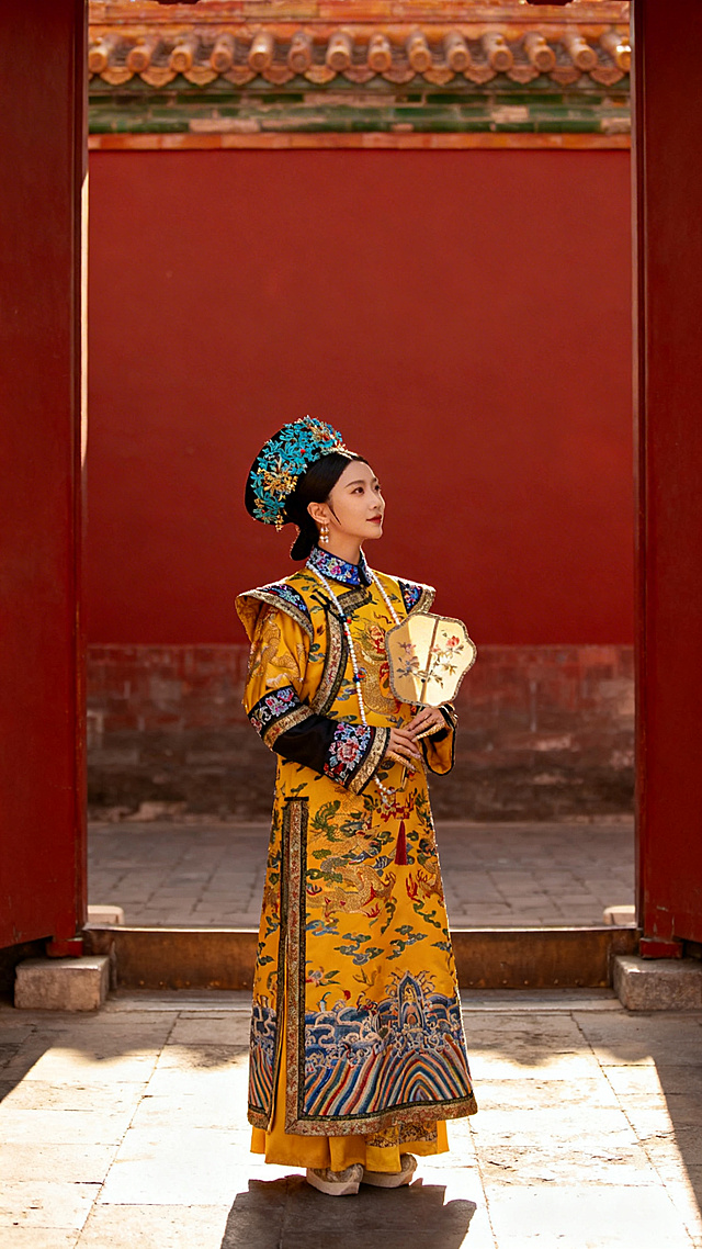 清代宫廷摄影风格，红墙宫苑中执团扇的妃嫔，对称构图，侧光，朱红明黄调，华丽旗装，点翠头饰