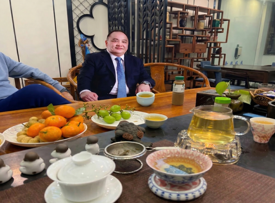 将图中男子面前的烟替换为图二中的白色茶杯，保持整体光影、场景自然融合，不改变原图其他内容预览效果