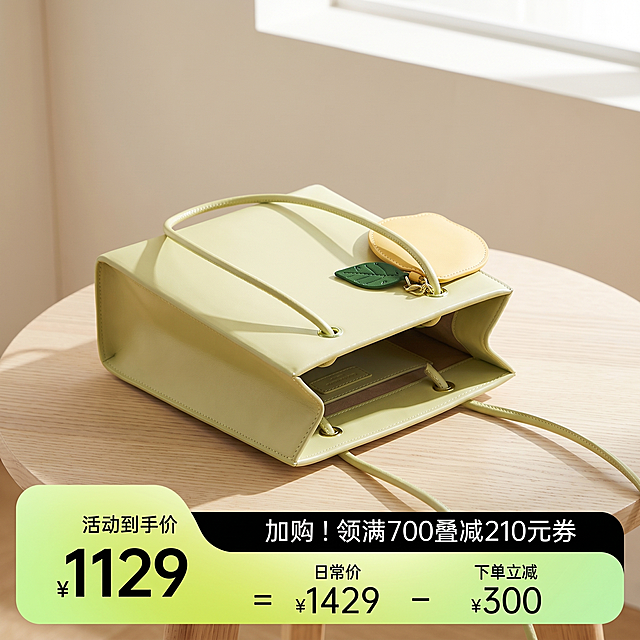 [主图 3] 浅黄绿色托特包侧面开口展示图。[氛围风格] 清新阳光自然风，春夏时尚氛围感。[画质] 商业摄影质感，光线柔和通透，产品清晰真实，画面干净高级。[元素] 浅黄绿色方形托特包放置在浅色木质桌面上，展示侧面开口结构和内部空间，包身轮廓完整，五金配件清晰，柠檬黄挂饰自然垂落。保持包包外观、物理结构、材质质感、颜色与输入产品图绝对一致，杜绝任何变形和色差。桌面干净整洁，背景虚化浅米色墙面，阳光透过窗户洒下自然阴影。商品主体占比约70%，画面满屏无边框。[光影] 自然散射太阳光，明暗对比清晰，突出包身材质和开口结构，光影柔和通透。[配色] 主色调浅黄绿色，原木浅棕+米白背景，整体清新干净。[视角构图] 45度俯视，清晰展示开口结构，景深适中。[文字版式] 无文字，纯产品展示。[比例分辨率] 1:1比例，2k分辨率，超高清。[负向提示词] 变形，水印，文字错乱，产品图模糊，背景杂乱，色差，遮挡主体