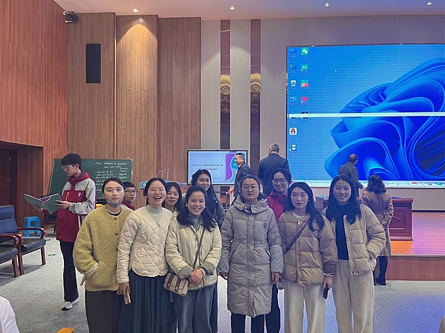 将第二张图中的女生自然地添加到第一张合照的右侧挨着其他人站立，不要替换合照中原有任何人物，保持整体画面光影和风格一致，融合自然真实