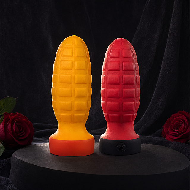 基于参考图中的两个硅胶产品（黄色和红色手雷造型硅胶物品），重新拍摄风格的产品精修图，高级暗调轻奢风。两个产品并排放置，左侧黄色底部橙红色，右侧红色底部黑色。强化硅胶真实质感：微哑光细腻肌理，边缘有柔和透光感，表面有细微颗粒质感。侧逆光打亮产品轮廓，形成漂亮的轮廓光，正面柔和补光，明暗对比分明，立体感强。背景为深灰色丝绒布料，质感高级，左下角和右下角各点缀一朵深红色玫瑰，简洁不杂乱。产品放置在深色哑光圆形台面上。整体氛围神秘高级，商业产品摄影质感，8K超清，细节丰富。