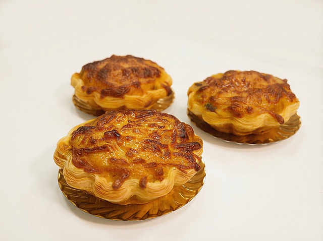 沿用之前暖色调温馨烘焙风格，制作这张三个芝士蛋挞的美食海报，保留三个金黄酥脆的蛋挞，优化蛋挞表面使其稍微光滑提升真实感，干净简洁画面，突出蛋挞酥脆层次和焦香芝士，预留海报文案位置