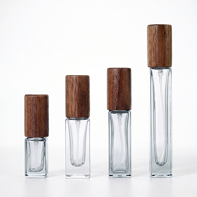 [Main Image 1] Flat glass perfume bottle with round wooden cap product main image. [Atmosphere Style] Clean, minimalist, high-end commercial product photography style. [Image Quality] Commercial photography texture, soft and transparent light, clear and real product, clean and high-end picture. [Elements] Four different sizes of flat glass perfume bottles (3ML, 5ML, 10ML short, 10ML elongated) are displayed in the center of a pure white background. The product is fully displayed without cropping, the product occupies 85% of the picture. Keep the appearance (physical structure, material texture, color) of the perfume bottle absolutely consistent with the input product picture, eliminate any distortion and color difference, fine processing. [Light and Shadow] Soft studio front lighting, clear texture of high transparent glass, natural wood grain texture highlights, soft shadow at the bottom, light transmission through the glass presents a clear three-dimensional sense, high light does not overflow, dark parts have layers. [Color Matching] Pure white background, main colors are transparent clear glass, natural black walnut brown, simple and high-end. [Perspective Composition] Flat overhead perspective, four bottles evenly arranged, centered composition, full picture without border. [Text Layout] No additional marketing text or logo, comply with Amazon cross-border platform main image regulations. [Proportion Resolution] 1:1 proportion, 2K resolution, super high definition. [Negative prompt] Deformation, watermark, text confusion, blurred product picture, messy background.