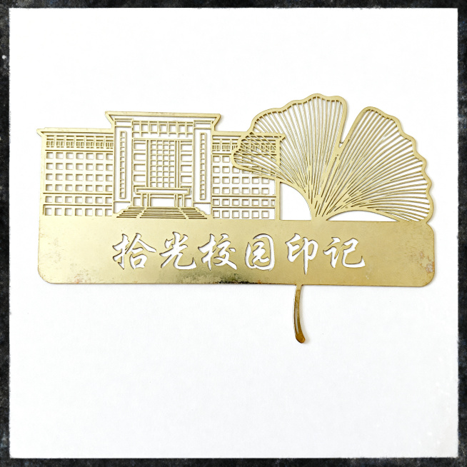 产品摄影，校园文创金属书签，主题为拾光校园印记，主体是学校标志性教学楼加银杏叶线稿，搭配手写体"拾光校园印记"字样，浅米白和淡金色配色，清新文艺风格，简约干净，高清细节，纯白背景，自然光，8K，无多余预览效果