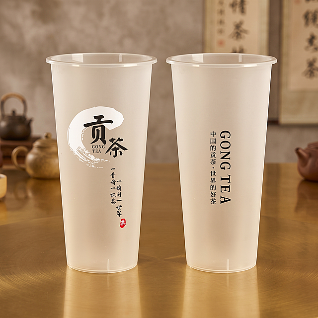 保持两个贡茶杯子的杯型不变，将两个杯子放置在同一个偏黄色调的台子/桌子上，扩展图片上下左右区域让整体画面更大，保证图文清晰