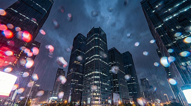 参考图片，仰拍高楼之间的天空，被雨水打湿的镜头，红蓝白城市的灯光引起的光晕（Bloom）散开，不要出现马路和车辆