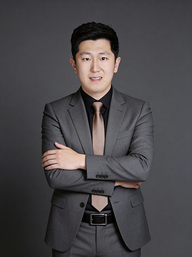 参考第一张图保留人物脸型､年龄等特征生成职场形象照,参考第二张图人物占位和比例,标准焦段50mm,F/4光圈(F/2.8-F/4区间),平视视角(镜头与人物视线齐平);人物占画面70%,人物居中(居中构图),位于画面中心,为视觉聚焦点,入境范围头部及以下至臀部区域(半身像);左右留少量背景空间;头部与画面顶部保留5%空间;头部发型完整;头肩比例协调,身穿修身精纺羊毛混纺面料的灰色西装,平驳领(商务感正式感),西装下摆自然垂度;内搭深色翻领衬衣,搭配高级浅咖色领带(含5%桑蚕丝提升柔光质感),下装精纺羊毛混纺面料的灰色西裤(面料同西装),搭配暗色哑光皮带(宽1.5cm),带扣为长方形拉丝黑色金属(1.8cm×2.5cm);呈正面抱胸的自然站立姿态:左臂搭于右臂上方,肩颈自然松弛下沉,姿态自信从容｡正式严谨专业稳重,身形匀称,姿态端正｡发梢微微修整干练大气,主体锐利,影棚侧光布光(主光来自画面前方),明暗过渡柔和,背景光线均匀,强化色彩对比的高级感｡哑光简约中深灰色纯色背景(呈现均匀柔和质感),极简干净;32K画质超高分辨率､细节清晰,整体风格雅致､兼具现代精致感;肤质精细化处理;眼神直视镜头,目光坚定且澄澈,表情自然.嘴角上扬;面部光比1:1.5,4800K中性光,微微修饰脸型,肤质哑光细腻,面部微微雾面柔光,轻透裸肌感,真实毛孔纹理,32K画质,去除人物之外的所有元素｡严格按照第一张图内容生成｡