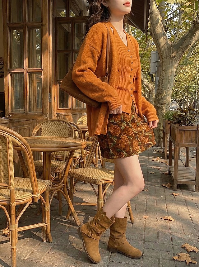 保留这套橘棕秋日穿搭，模特改为双手轻轻提起裙摆侧身展示姿势，复古咖啡馆梧桐露台午后暖光，突出碎花裙花色和穿搭层次感，抖音带货风格，凸显服饰细节