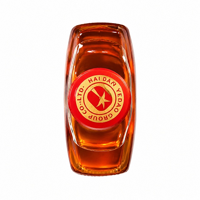 将参考图中的椰岛臻补酒臻品小瓶（顶部俯视视角，红色瓶盖带金色品牌logo）进行电商级精修，置于纯净的纯白背景上，极致展现玻璃的通透质感与琥珀色酒液的精准色泽，酒液颜色为统一的透亮琥珀橙红色，呈现高级光泽与闪耀感，产品完美无瑕，清除所有指纹、灰尘、划痕，突出产品的立体感，商业级广告画质，1:1正方形构图