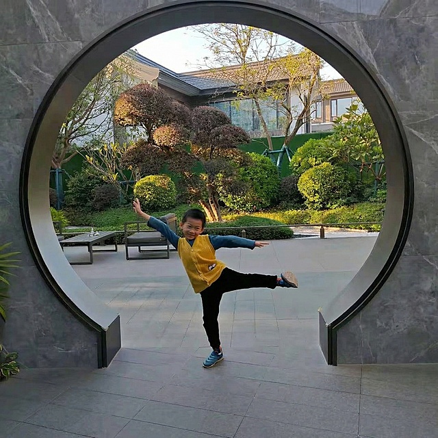 补全图片中的圆形门洞，让门洞为完整的正圆形，和现有画面的材质、风格保持一致，中式庭院场景和人物保留不变