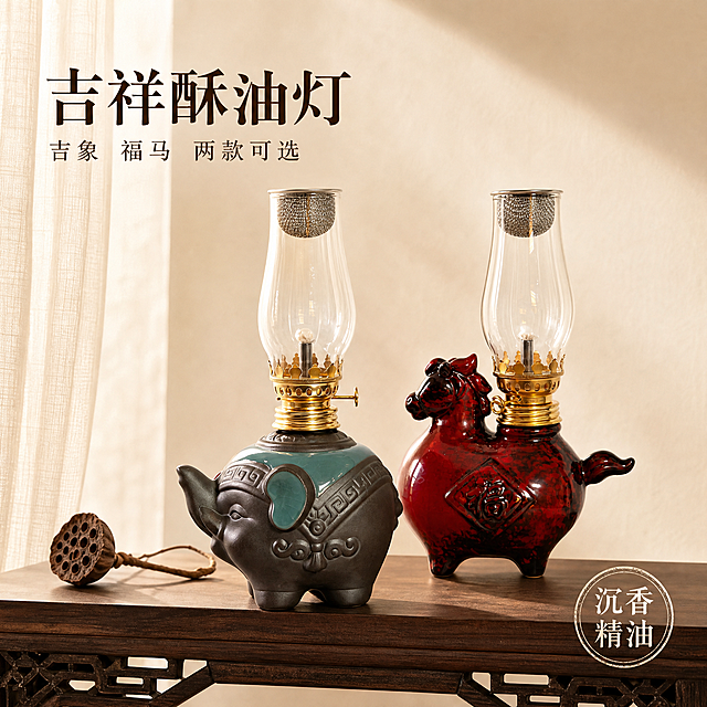 新中式简约风格电商主图，两款酥油灯并排陈列在深胡桃木案几上，左侧是吉象酥油灯（灰绿陶瓷大象造型+金色灯头+玻璃灯罩），右侧是福马酥油灯（红釉陶瓷马造型+金色灯头+玻璃灯罩）。两款产品外观均与各自原图完全一致，陶瓷质感、金色灯头纹理、玻璃灯罩通透感均保持不变。背景是极简新中式空间，浅米色墙面，左侧半透米白纱帘，暖黄色柔和侧光打在陶瓷和玻璃上，形成优美高光。案几上有一小枝干枯莲蓬点缀。左上文字：大字"吉祥酥油灯"深棕色宋体，小字"吉象 福马 两款可选"。右下圆形印章式标签"沉香精油"。整体色调暖棕金，留白充足，雅致高级，商业摄影质感。1:1正方形构图，2K超高清。
