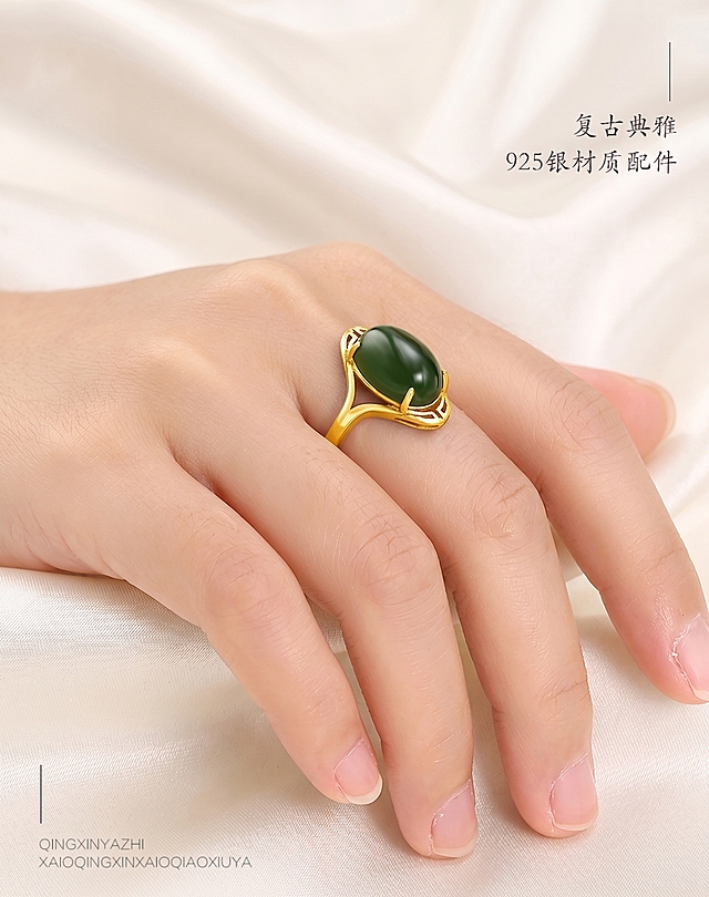 将戒指金属部分颜色修改为亮金色，保持绿色玉石、手部、产品细节和所有文字内容不变，背景替换为高级质感的米白色丝绸
