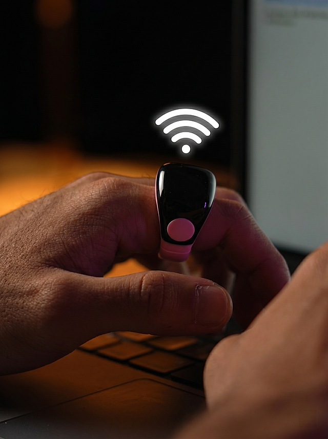 参考图2的场景：室内暖光氛围，深色背景，带wifi信号图标，手指托住戒指的姿势，将图1的粉黑拼色智能戒指放入该场景，保持戒指原有粉黑配色和粉色按钮，添加wifi信号图标在戒指上方，生成商业展示图，输出尺寸900*1200像素