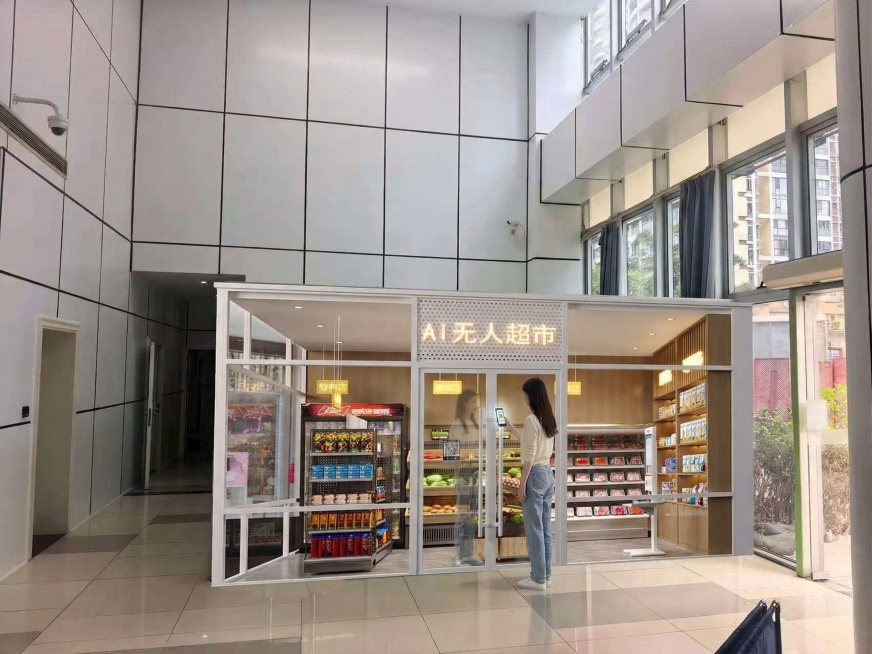 保持图1中AI无人超市的整体场景、大小、环境完全不变，在无人超市的玻璃门口添加和图2中完全一样的女生（米白色上衣、蓝色牛仔裤、白色鞋子，深色长发），女生正手持手机对着门口的扫码设备扫码准备进门，整体风预览效果