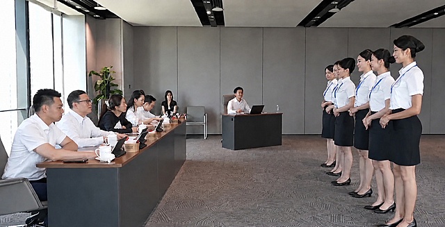 去除图片左上角的蓝色台标logo，保持画面其他所有内容不变，人物面部完全保留不动，修复后的区域要与周围窗户和墙面自然融合，看不出修改痕迹。注意：不要修改人物、不要改变场景布局，只去掉左上角的蓝色台标