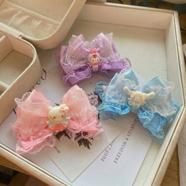 【最高指令：保留所有细节】完全保留原图三款不同颜色（粉色HelloKitty、紫色库洛米、蓝色玉桂狗）卡通公仔蕾丝蝴蝶结发夹的所有细节、原有位置和造型不变，更换为参考图一样放置在浅色礼盒内的场景，生成预览效果