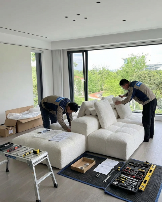 室内安装现场，只需要两个工人，工人衣服上写着BUNISE的logo。画面明亮清晰，整体氛围专业有序。安装人员在室内进行家具安装与调试，动作规范、细致。工具摆放整齐，安装流程清楚可见。空间干净整洁，体现预览效果