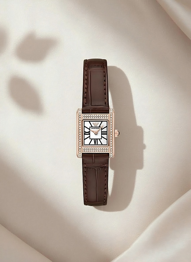 浅米色的丝绸做空间感的背景，珍珠般的光泽感，光线柔和，光线从左侧照射过来，手表右侧有阴影，手表平方在丝绸中，背景中非常浅的有两三片树叶的倒影