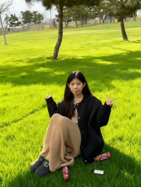 保持人物和前景不变，将人物后方的枯草地替换为茂盛的绿色草坪，和前景草坪风格自然衔接，保留树木和远景场景不变，整体光影和谐自然预览效果