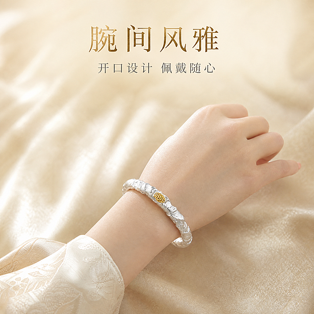 [主图-3] 足银描金莲花手镯佩戴展示图，手模佩戴展示上手效果与镯型尺寸比例。
[统一基调] 国风雅致高级质感，背景为浅香槟色丝绒质感，柔光箱高光勾勒金属轮廓，字体采用纤细宋体国风字体，主标题字色为深金色，辅助字色为暖灰色，整体克制精致。
[画面] 一只东方女性的手自然舒展，手腕纤细白皙，皮肤细腻，手镯佩戴在手腕正中位置，正面莲花描金朝向镜头，开口处位于手腕内侧隐约可见。手呈自然放松姿态，手指微微弯曲，展示手镯佩戴后的圈口大小与整体比例。背景为浅香槟色丝绒虚化背景，突出手腕与手镯主体。画面上方留白处放置佩戴氛围文案。主体（手+手镯）占比约60%。
[光影质感] 柔和自然光感，主光从前方打下，手镯银质部分呈现温润光泽，描金莲花蕊有温暖高光，手腕皮肤质感细腻真实，手镯与皮肤接触处有自然阴影。
[配色] 背景浅香槟色虚化，手镯银色+金色描金，手部自然肤色，标题深金色，辅助文字暖灰色。
[文字版式] 画面上方居中两行文案：第一行大字「腕间风雅」，第二行小字「开口设计 佩戴随心」。文字放置在画面上方负空间，不遮挡手和手镯。
[输出要求] 比例1:1，手部形态自然无畸形，手镯佩戴位置真实不悬浮，产品外观与输入图一致，文字清晰，无水印、无平台Logo、无多余杂物。