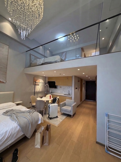 在下铺床上搭放一条休闲毯子，在下铺床旁边的木地板空地上放置两个简约购物袋，保持原有loft轻奢浅灰空间风格和其他元素不变，整体协调自然预览效果