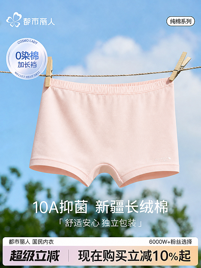 将图中原来的米白色内裤替换为上传的浅粉色儿童平角内裤，保持整体构图不变：内裤用木衣夹夹在绳子上悬挂，背景保留蓝天和绿植，保留原有全部文案：都市丽人、纯棉系列、0染棉加长裆、10A抑菌 新疆长绒棉、舒适安心 独立包装、都市丽人 国民内衣、6000W+粉丝选择、超级立减 现在购买立减10%起，整体风格清新自然