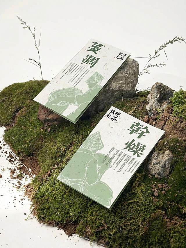 将图1的折页放着在图2的场景中，折页垫一块天然岩石，表面覆盖青翠苔藓，整体构图简洁自然，比例需要正确，背景为纯净米白色，光线柔和均匀，保留贴纸细节，让画面和谐统一，突出材质细节与静谧氛围，8K高清，新中式自然美学，产品摄影风格。