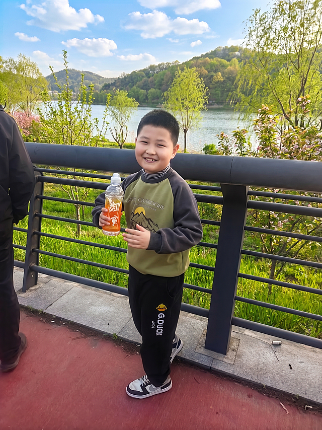 将背景美化成生机勃勃的春天景色，把枯黄的野草和树木替换为鲜嫩翠绿的绿植，整体色调清新自然，充满春日绿意，保持人物主体不变