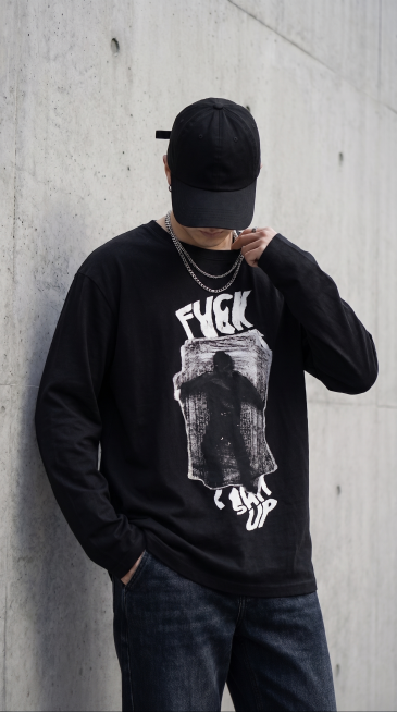 基于原图生成，更换为全新的动作和不同拍摄角度的上半身照片，保留黑色纯棉宽松长袖T恤和潮牌涂鸦印花，黑色帽子依旧压低完全遮挡脸部，搭配银饰项链，保持水泥墙面简约街头室外场景，自然光影，高级生活化色调，高预览效果