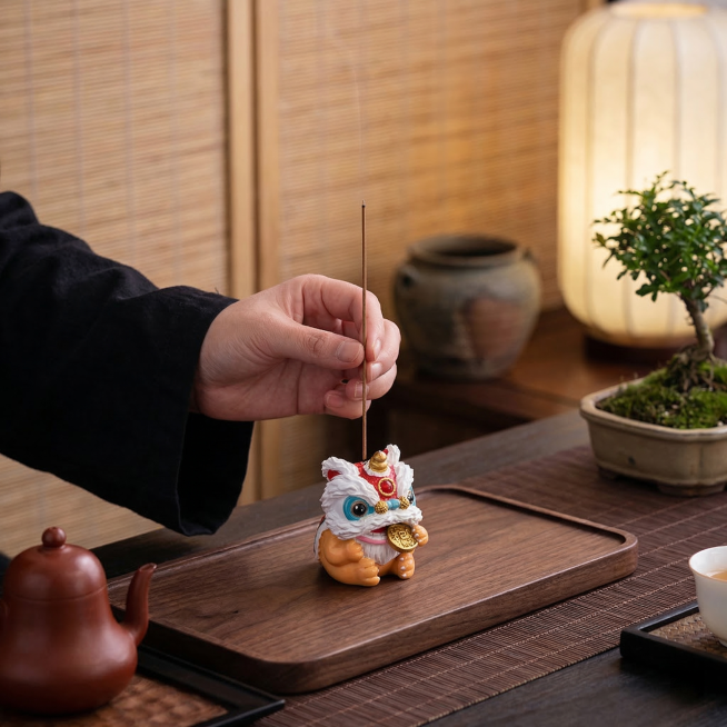 保留主体醒狮香插、手、香、茶壶所有细节和结构不变，移除所有文字和上方留白，更换为新中式禅意茶室背景，保持产品纹理和颜色不变，自然柔和侧光，深胡桃木茶席，氛围静谧雅致，商业静物摄影，方形构图，画面细腻写预览效果