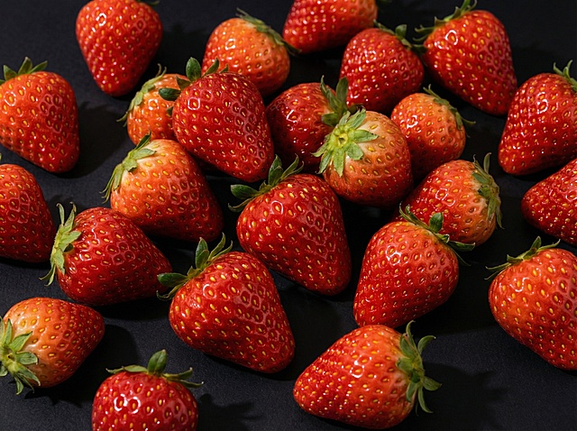 将背景替换为高级哑光黑色，调整光影为柔和侧光，凸显草莓的质感和色泽，提升整体高级感